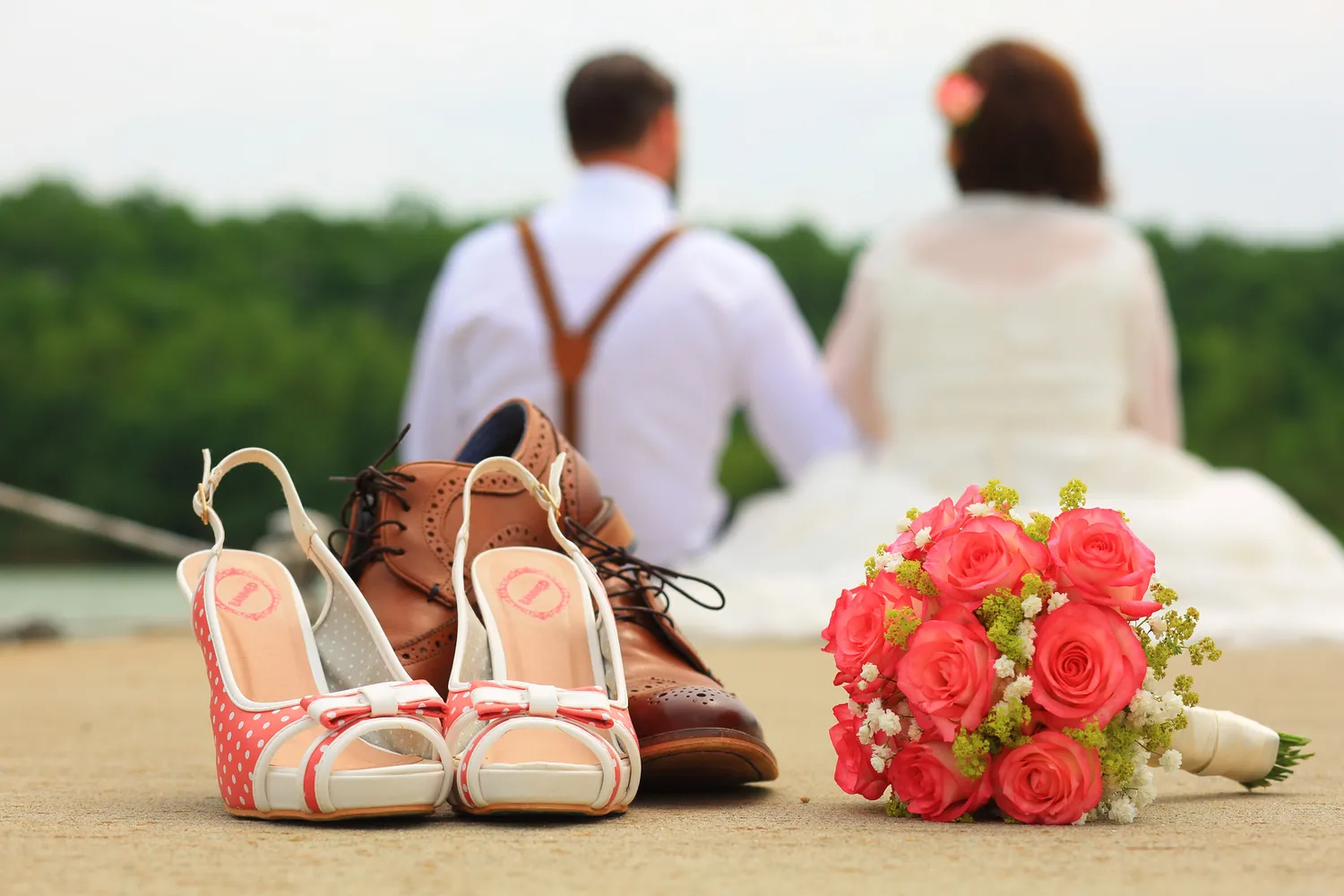 Brautschuhe und Strauß mit dem Paar im Hintergrund